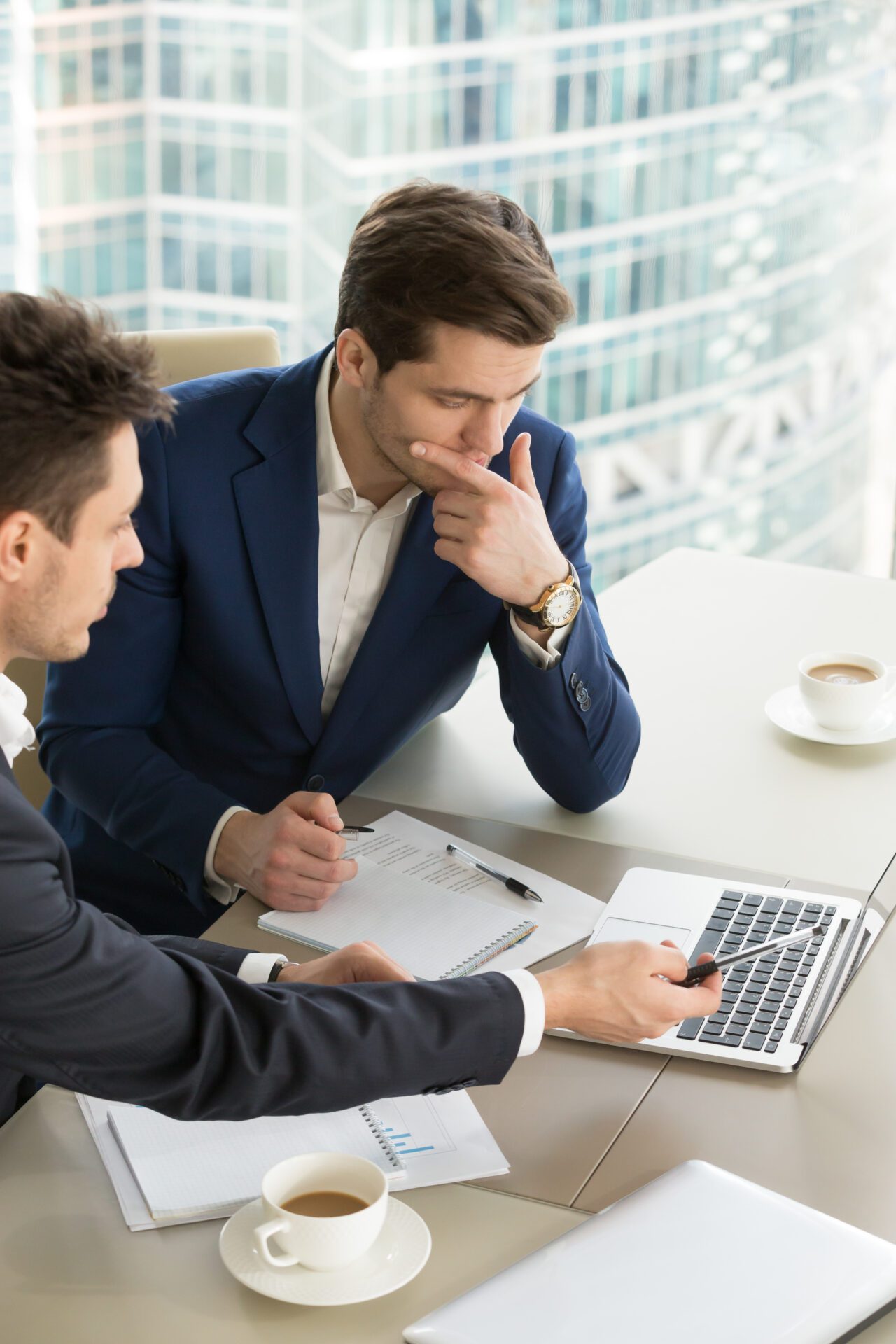 Business partners using laptop while working together on important corporate project in office. Businessman attentively listening to adviser Investment specialist making presentation of promising deal